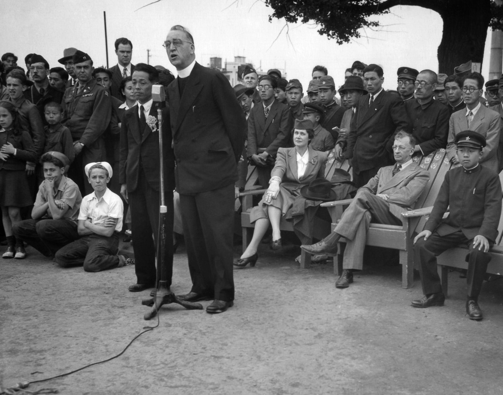 FILE - Father Edward J. Flanagan, founder of Boy's Town, Nebraska, speaks into a microphone at Meiji Stadium in Tokyo, May 28, 1947 during a Japanese Boy Scout Jamboree. At right, wearing his school uniform, is Crown Prince Akahito. (AP Photo/Charles Gorry, File)
