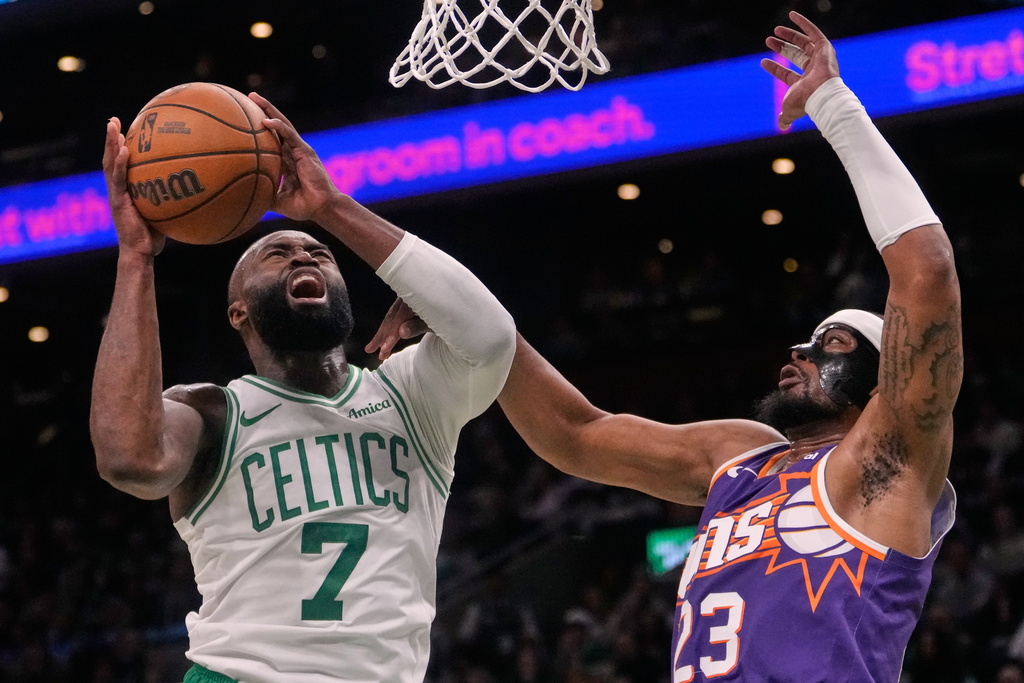 Boston Celtics guard Jaylen Brown (7) is fouled by Phoenix Suns guard Jordan Goodwin (23) on a drive to the basket during the first half of an NBA basketball game, Monday, March 16, 2026, in Boston. (AP Photo/Charles Krupa)
