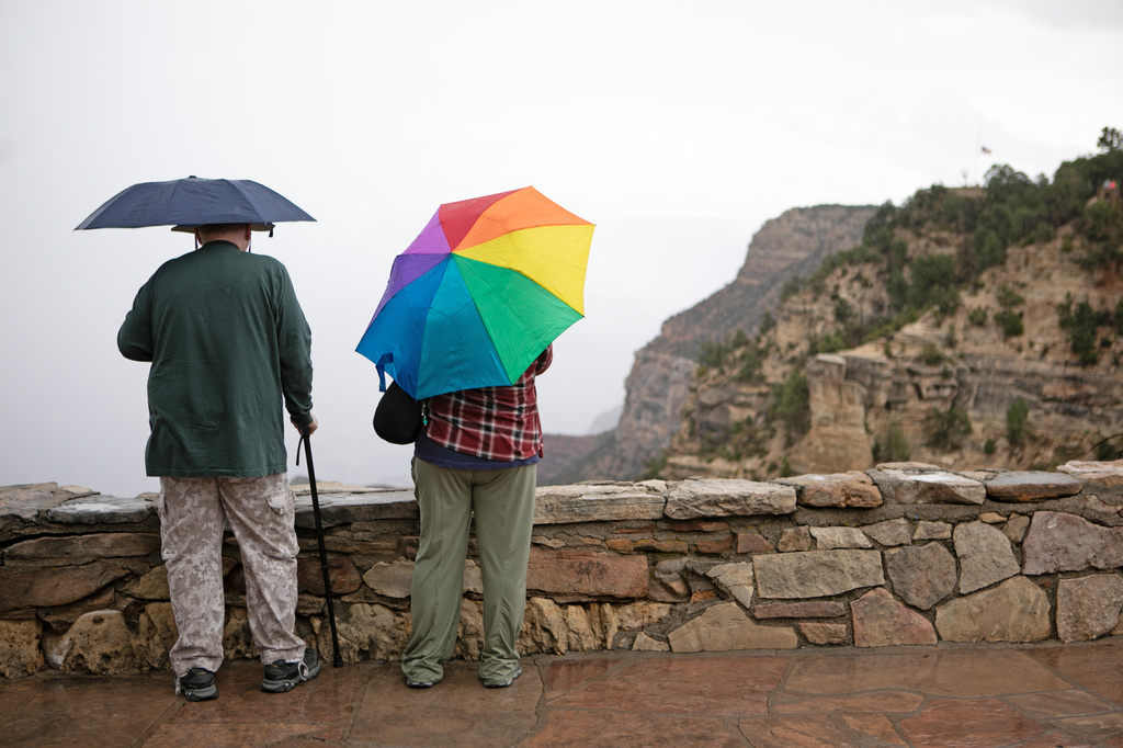 Tourists look over the rim of the Grand Canyon in the rain, Monday, Aug. 31, 2026, in Grand Canyon National Park, Ariz. (AP Photo/Josh Biggs)