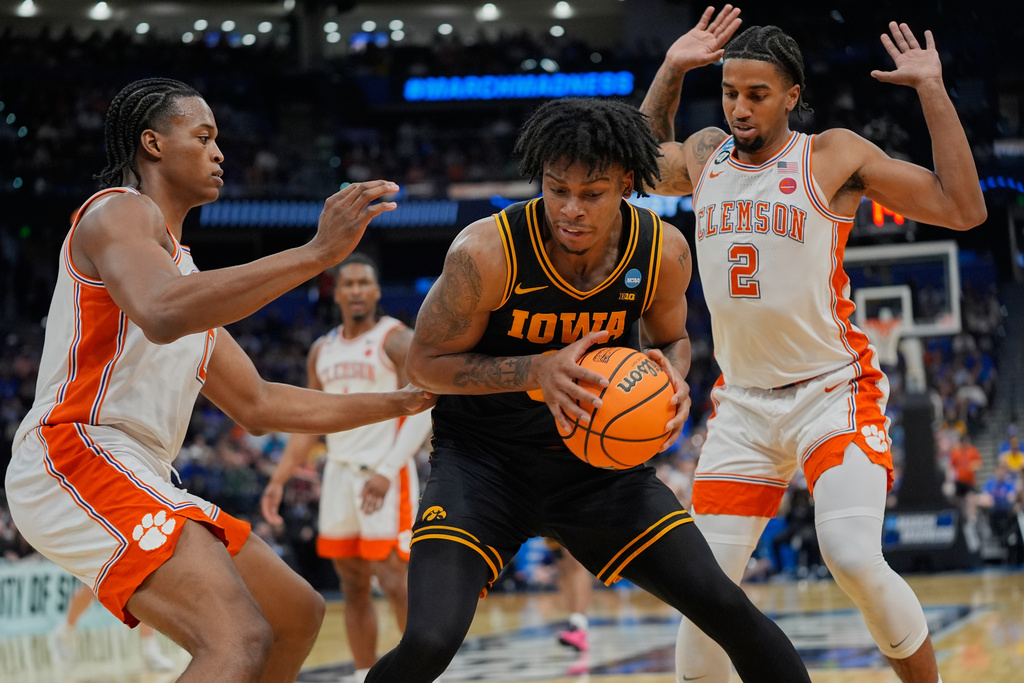 Iowa guard Tavion Banks, center, tries to get from around Clemson forward RJ Godfrey, left, and guard Dillon Hunter (2) during the first half in the first round of the NCAA college basketball tournament, Friday, March 20, 2026, in Tampa, Fla. (AP Photo/John Raoux)