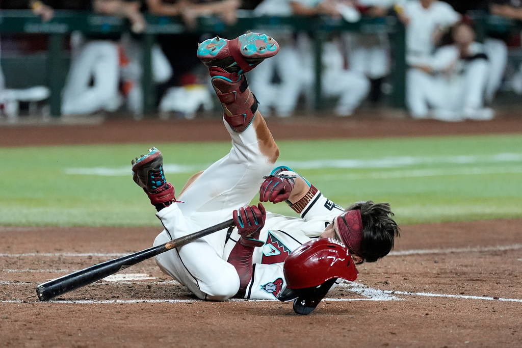 Arizona Diamondbacks' Corbin Carroll hits the ground after being brushed back on an inside pitch against the Los Angeles Dodgers during the third inning of a baseball game Wednesday, Sept. 24, 2025, in Phoenix. (AP Photo/Ross D. Franklin)