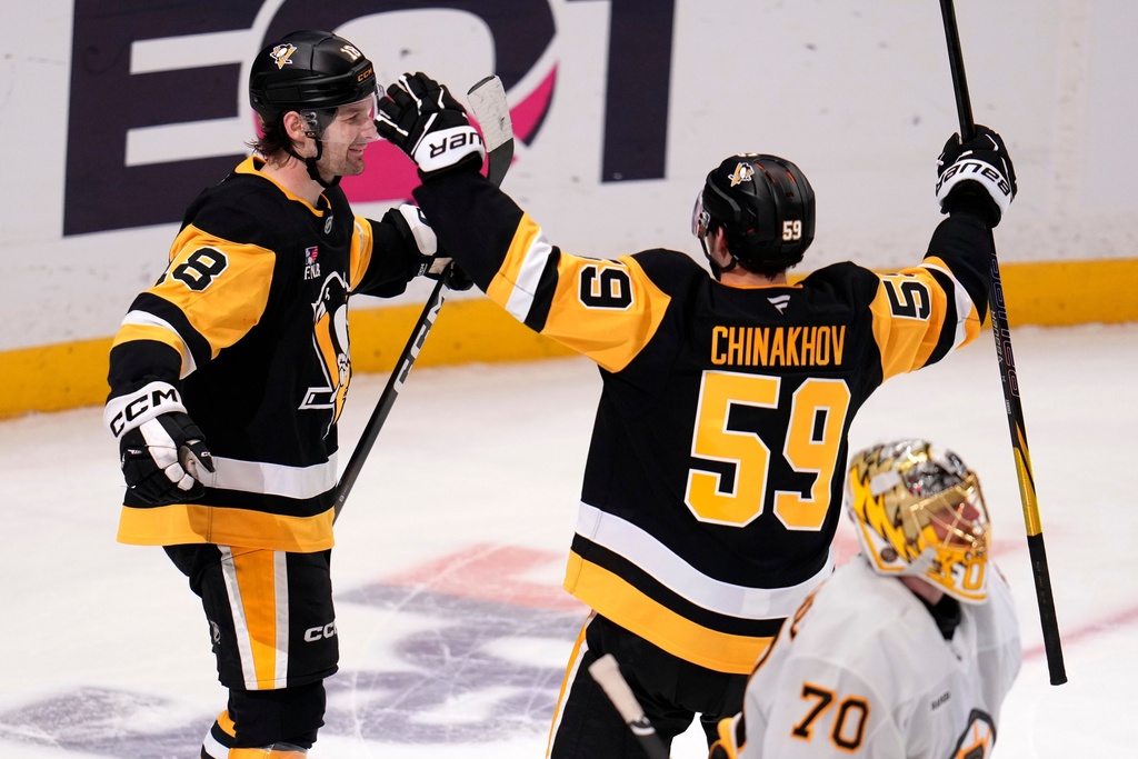 Pittsburgh Penguins' Tommy Novak, left, celebrates his game-winning overtime goal with Egor Chinakhov (59) as Boston Bruins goaltender Joonas Korpisalo (70) skates to the locker room at the end of an NHL hockey game in Pittsburgh, Sunday, March 8, 2026. (AP Photo/Gene J. Puskar)