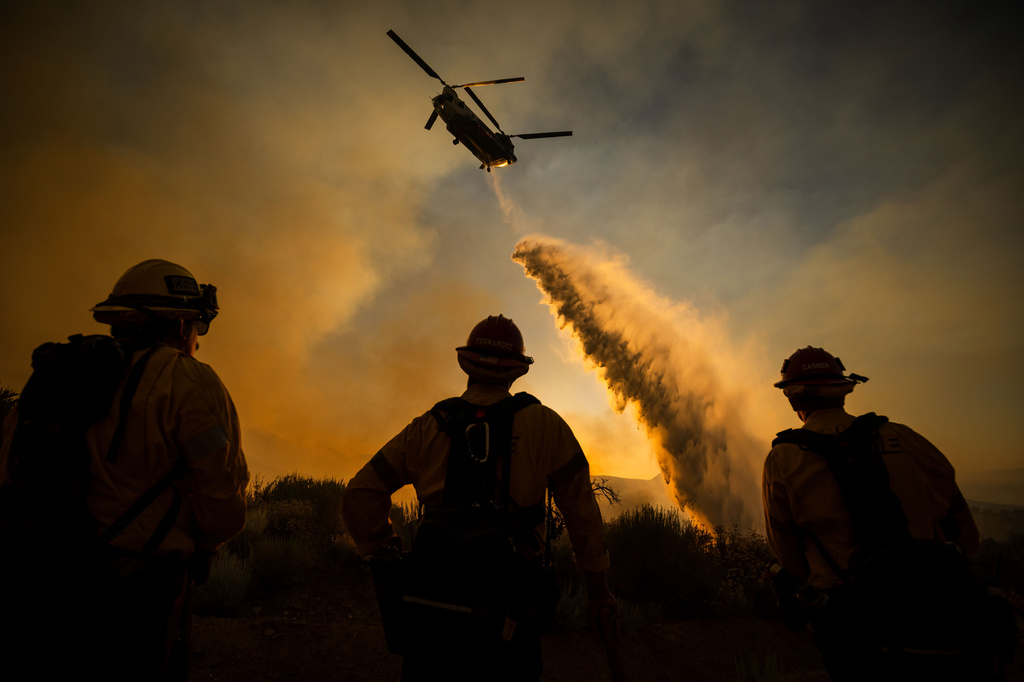Firefighters watch as a helicopter drops water on the Summit Fire in Llano, CA. Friday, July 10, 2026. (AP Photo/Ethan Swope)