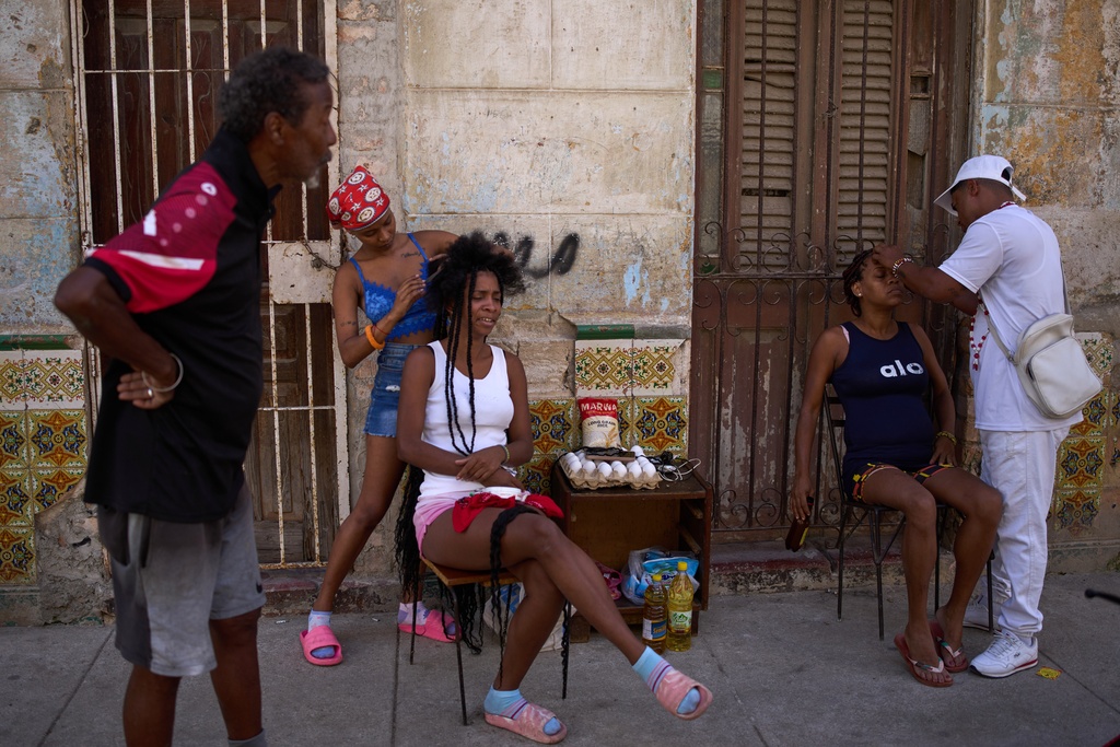 Hairdressers style the hair of their clients in the open air during a blackout in Havana, Cuba, Thursday, March 5, 2026. (AP Photo/Ramon Espinosa)