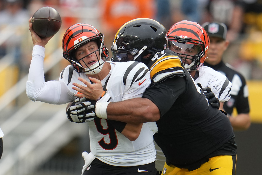 Cincinnati Bengals quarterback Joe Burrow, left, throws as he is tackled by Pittsburgh Steelers defensive tackle Cameron Heyward, right, during the second half of an NFL football game in Pittsburgh, Sunday, Sept. 27, 2026. (AP Photo/Gene J. Puskar)