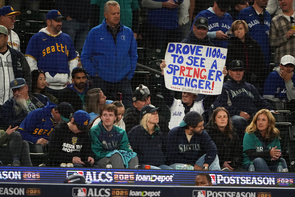 A Toronto Blue Jays fan holds a sign for George Springer during Game 3 of baseball's American League Championship Series between the Blue Jays and the Seattle Mariners, Wednesday, Oct. 15, 2025, in Seattle. (AP Photo/Lindsey Wasson)