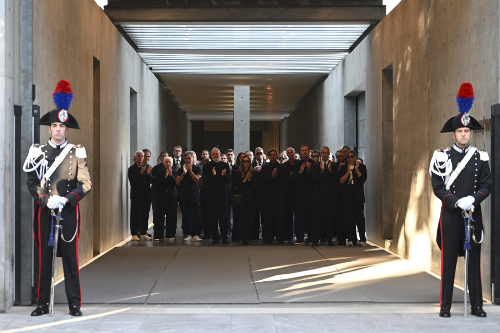 Staff of Giorgio Armani Spa gather outside the Armani/Teatro in Milan, northern Italy, as the hearse with the casket of designer Giorgio Armani, who died Thursday at age 91, leaves, Sunday, Sept. 7, 2025. (AP Photo/Nicola Marfisi)