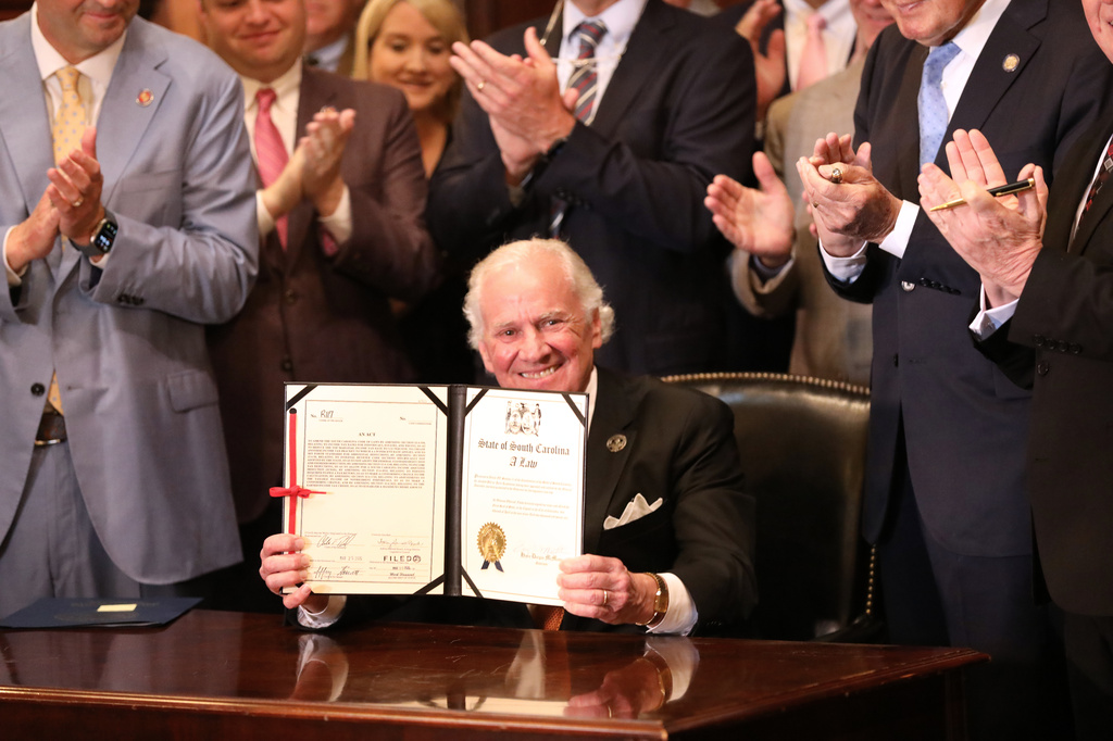 Republican South Carolina Gov. Henry McMaster holds up a ceremonial copy of a bill that simplifies the state tax code and sets a framework to reduce the income tax rate on Wednesday, April 15, 2026, in Columbia, S.C. (AP Photo/Jeffrey Collins)