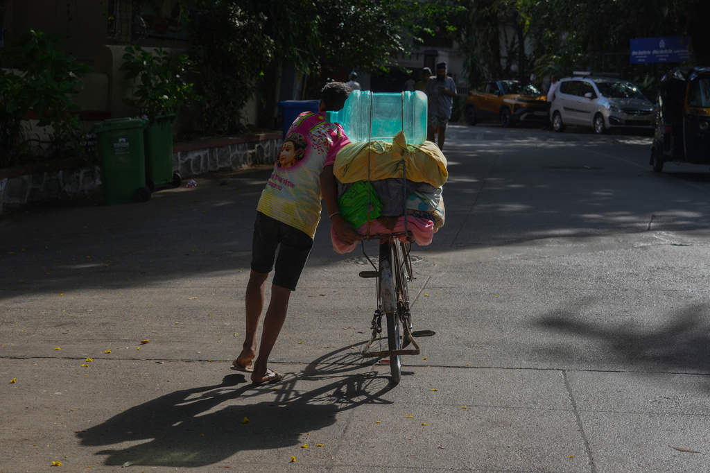 A washerman carries a water can on his bicycle on a hot day in Mumbai, India, Saturday, June 20, 2026. (AP Photo/Rafiq Maqbool)