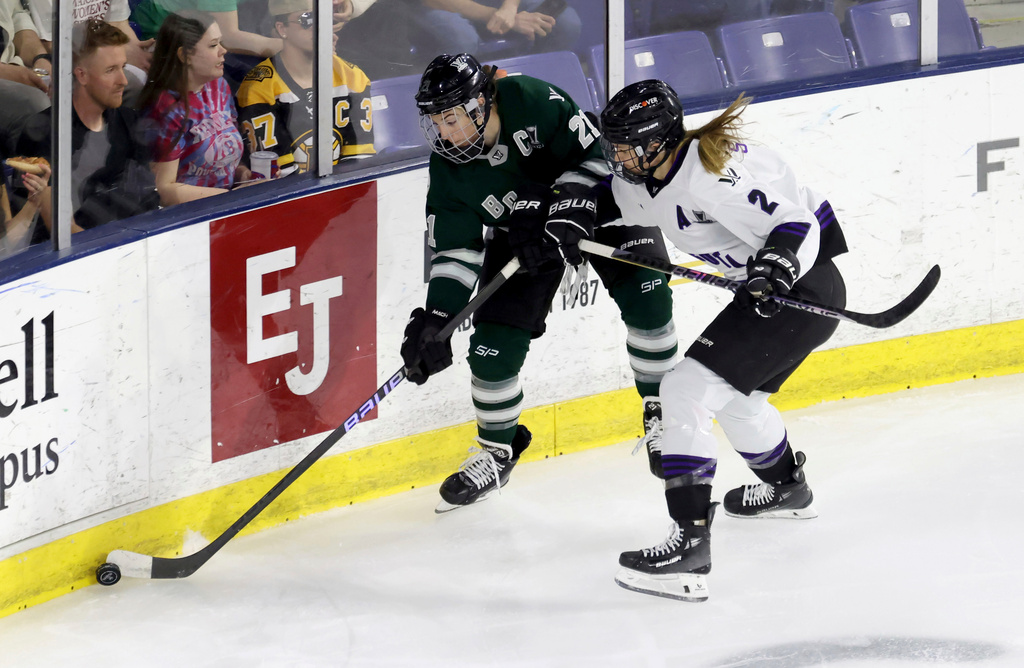 FILE - Boston forward Hilary Knight (21) and Minnesota defender Lee Stecklein (2) chase the puck against the boards during the first period of Game 2 of a PWHL hockey championship series, May 21, 2024, in Lowell, Mass. (AP Photo/Mark Stockwell, File)