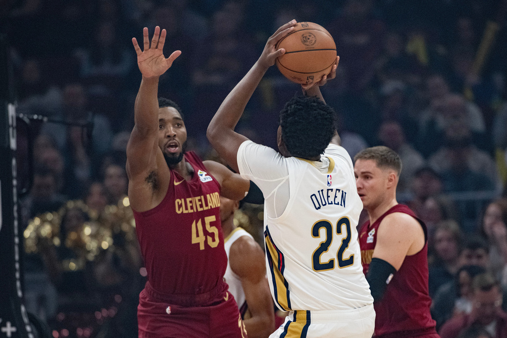 Cleveland Cavaliers' Donovan Mitchell (45) defends as New Orleans Pelicans' Derik Queen (22) shoots during the first half of an NBA basketball game in Cleveland, Tuesday, Dec. 23, 2025. (AP Photo/Phil Long)