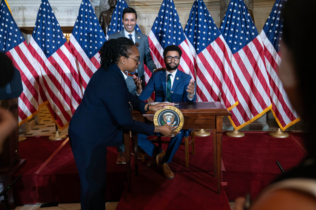Rep. Suhas Subramanyam, D-Va., left, and Rep. Maxwell Frost D-Fla., speaks at a desk prepared for President Donald Trump as an official removes the presidential seal, after President Trump canceled the signing the bipartisan Housing Bill on the Capitol Wednesday, June 24, 2026, in Washington. (AP Photo/Jose Luis Magana)