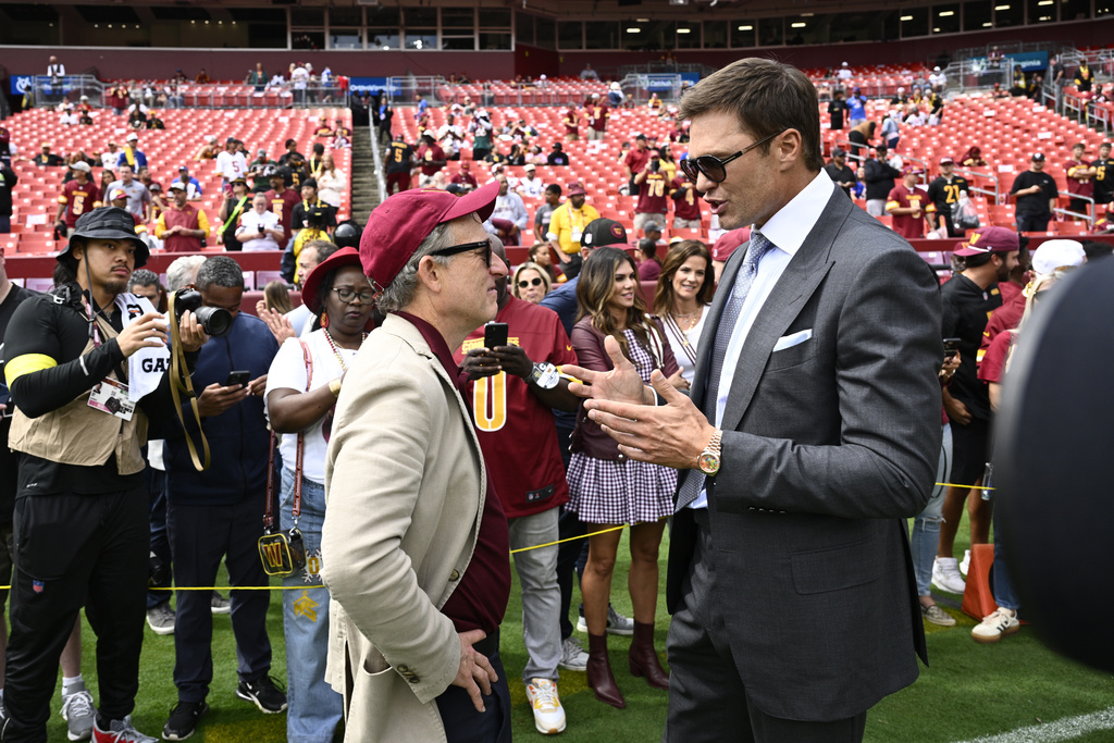 Washington Commanders owenr Josh Harris, right, talks with former NFL quarterback Tom Brady, right, before the start of an NFL football game against the New York Giants, Sunday, Sept. 7, 2025, in Landover, Md. (AP Photo/Nick Wass)