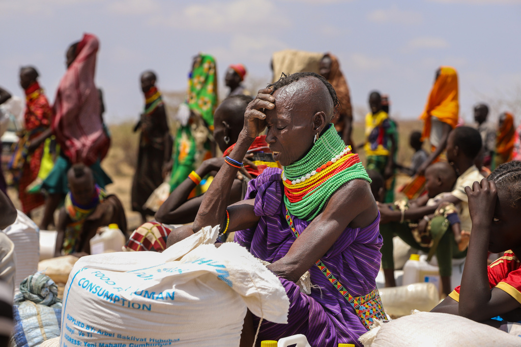 An elderly Turkana woman covers herself from the hot sun after receiving her food ration, in Lomeluku Village, Turkana County, Kenya, Sunday, Feb. 8, 2026. (AP Photo/Patrick Ngugi)