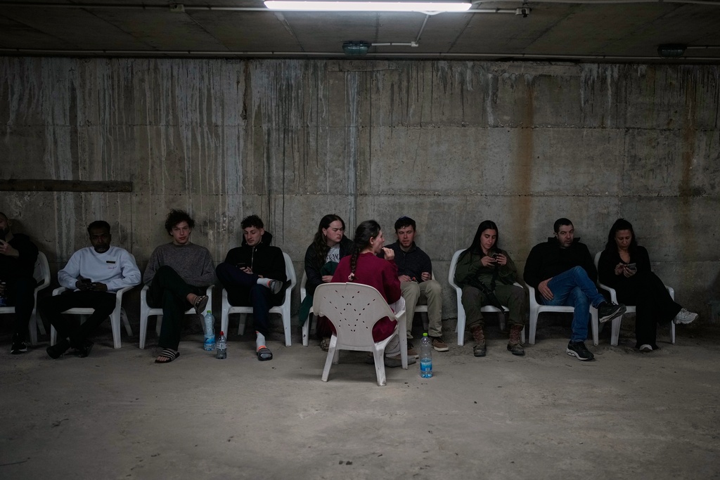People sits in a shelter after warning sirens sound following Israeli strikes on Iran, in Tel Aviv, Israel, Saturday, Feb. 28, 2026. (AP Photo/Ohad Zwigenberg)