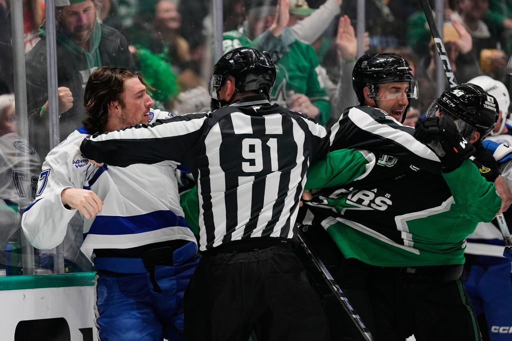 Tampa Bay Lightning defenseman Declan Carlile, left, is held back by linesman Ben O'Quinn (91) as Carlile and Dallas Stars' Justin Hryckowian, right, fight in the first period of an NHL hockey game in Dallas, Sunday, Jan. 18, 2026. (AP Photo/Tony Gutierrez)