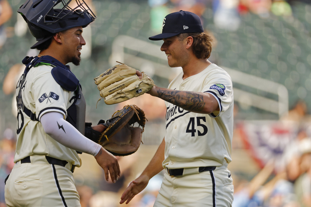 Minnesota Twins catcher Jhonny Pereda, left, celebrates with relief pitcher Travis Adams, right, after a win over the Cleveland Guardians in a baseball game Sunday, Sept. 21, 2025, in Minneapolis. (AP Photo/Bruce Kluckhohn)