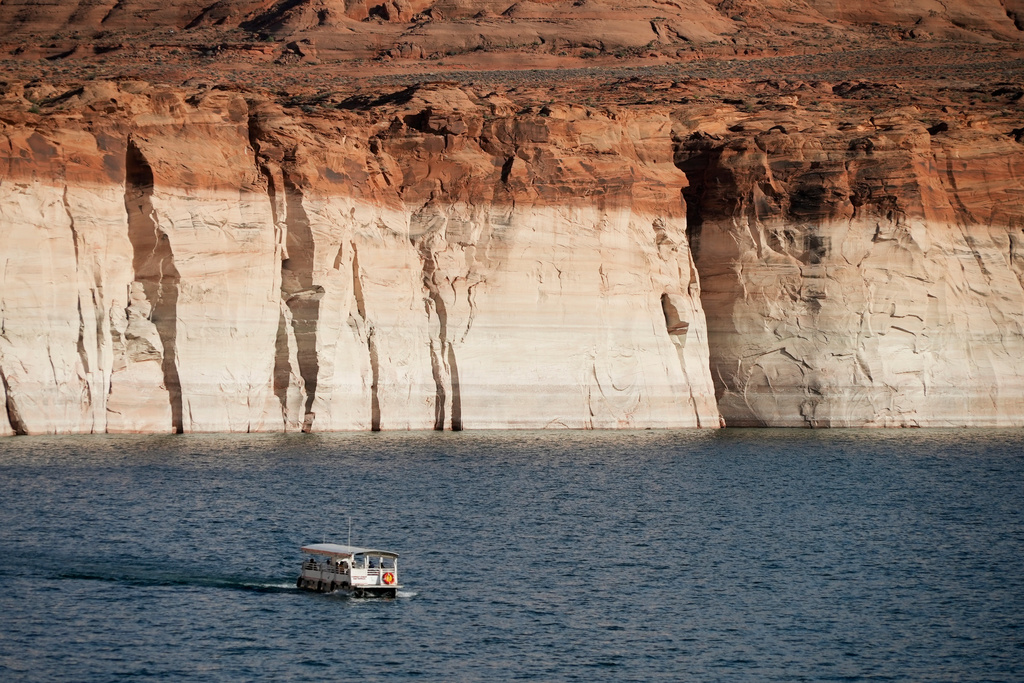 FILE - A boat floats past bathtub rings showing how low Lake Powell levels have dropped June 7, 2022, in Page, Ariz. (AP Photo/Brittany Peterson, File)