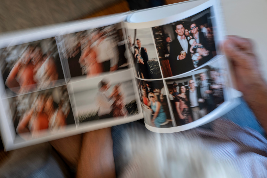 Christy Morrill, 72, who lost decades of memories to autoimmune encephalitis, looks over a photo album of his son's wedding, at his home, Tuesday, Aug. 19, 2025, in San Carlos, Calif. (AP Photo/David Goldman)