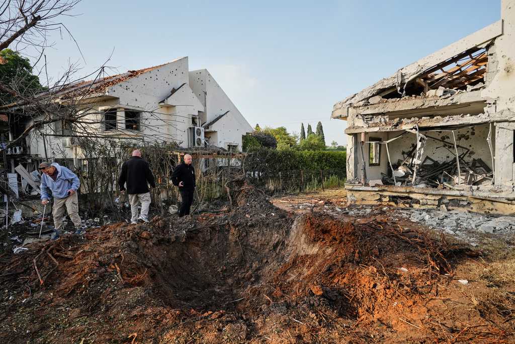 People inspect homes damaged by a projectile launched from Lebanon, in Haniel central Israel, Thursday, March 12, 2026. (AP Photo/Baz Ratner)