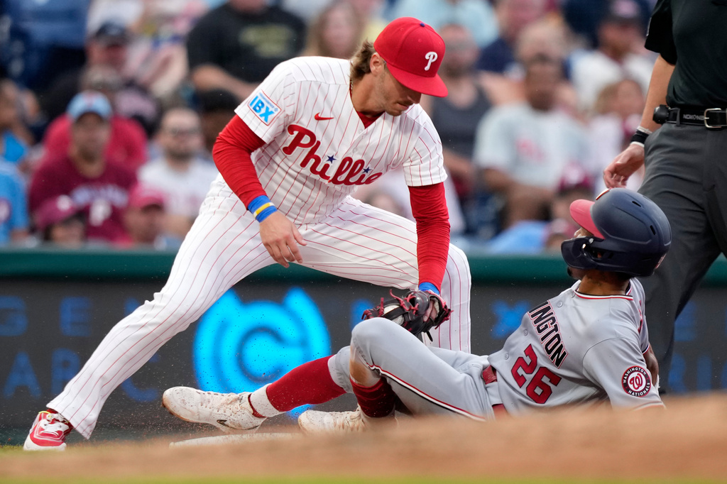 Philadelphia Phillies third baseman Bryson Stott, left, tags out Washington Nationals' Nasim Nuñez after he tries to steal third during the third inning of a baseball game Tuesday, Aug. 4, 2026, in Philadelphia. (AP Photo/Matt Slocum)