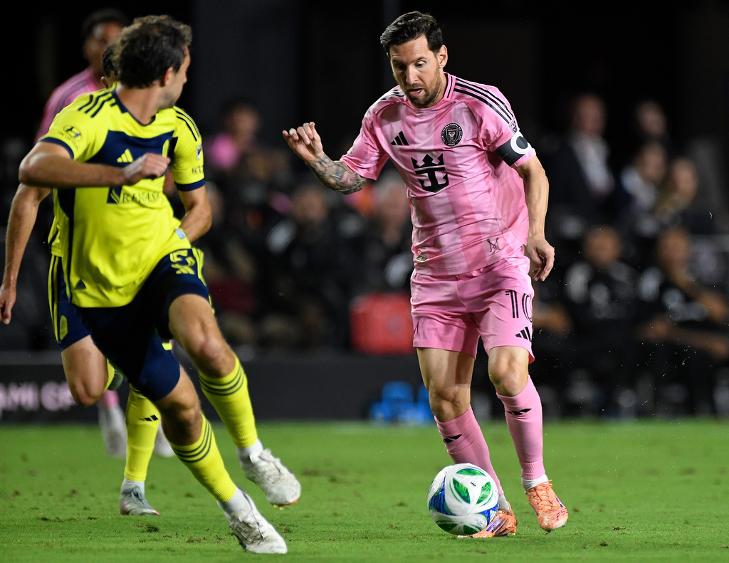 Inter Miami forward Lionel Messi, right, challenges Nashville SC defender Jack Maher, left, during the first half of Game 3 in the first round of MLS soccer's Western Conference playoffs in Fort Lauderdale, Fla., Nov. 8, 2025. (AP Photo/Michael Laughlin)