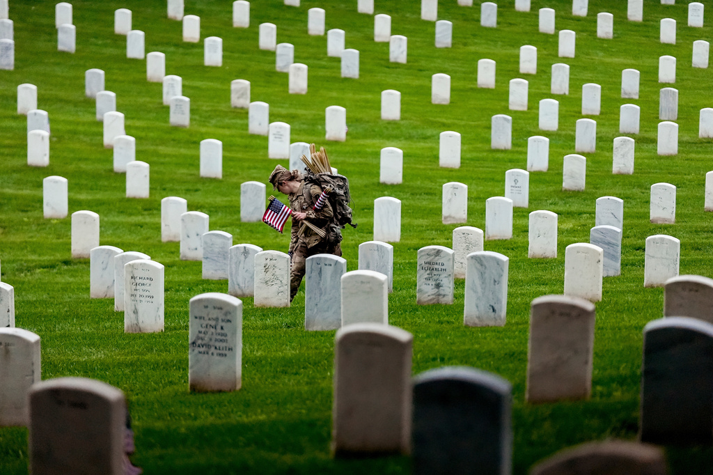 FILE - A member of the 3rd U.S. Infantry Regiment places flags at the headstones of service members buried at Arlington National Cemetery ahead of Memorial Day, May 22, 2025, in Arlington, Va. (AP Photo/Julia Demaree Nikhinson, File)