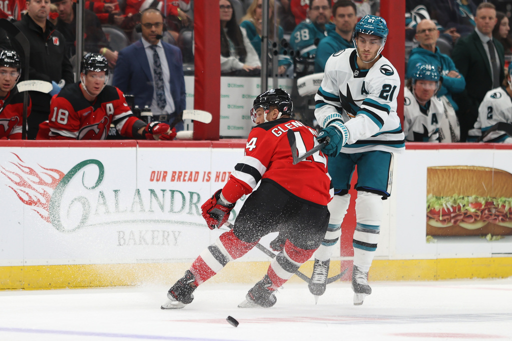 New Jersey Devils' Luke Glendening, left, and San Jose Sharks' Alexander Wennberg, right, compete for the puck during the first period of an NHL hockey game Friday, Oct. 24, 2025, in Newark, N.J. (AP Photo/Pamela Smith)