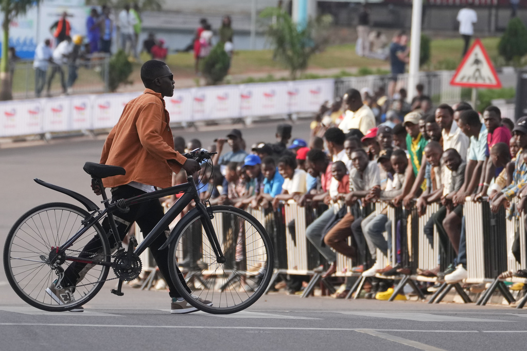 A man pushes his bicycle as he crosses the road during the team time trial mixed relay event, at the road cycling World Championships in Kigali, Rwanda, Wednesday, Sept. 24, 2025. (AP Photo/Jerome Delay)