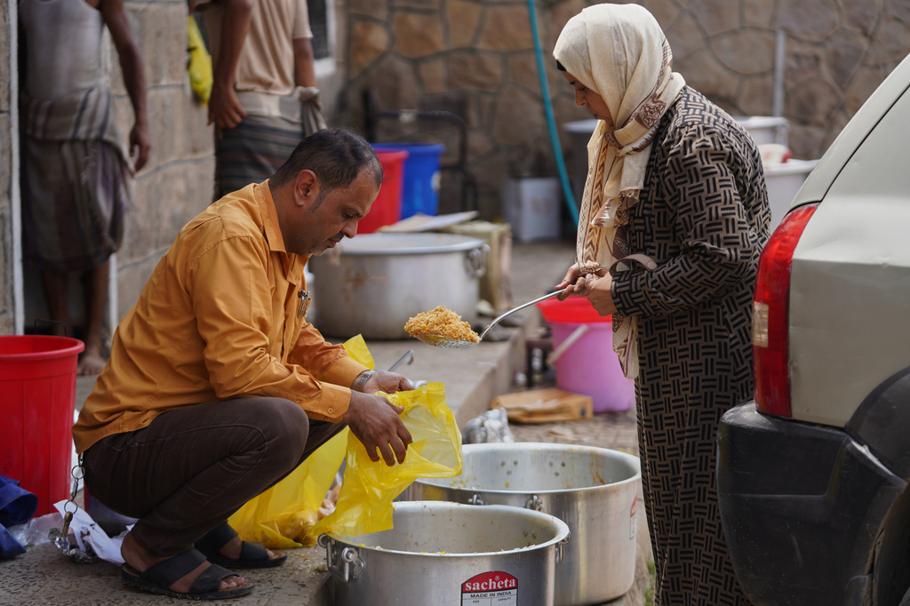Volunteer Naseem Al-Adini, right, provides free meals to displaced people at the Al-Akdaf camp in Taiz, Yemen, Saturday, Sept. 26, 2026. (AP Photo/Abdulnasser Alseddik)