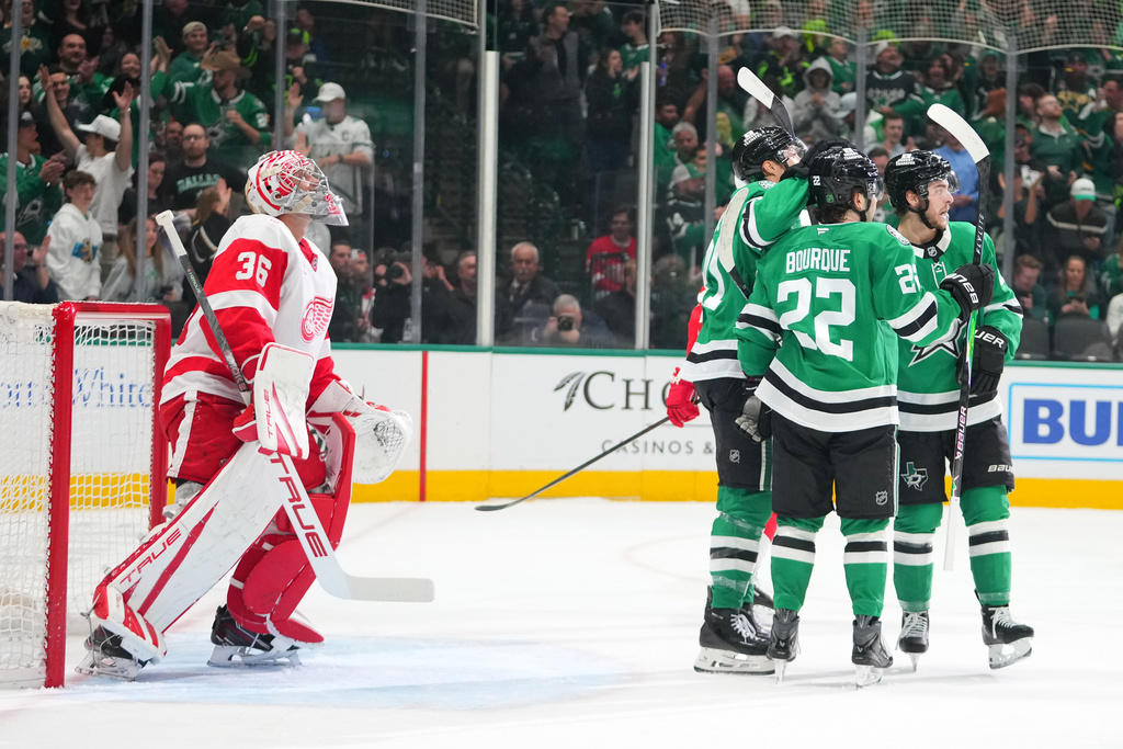 Dallas Stars center Wyatt Johnston, right, celebrates his first period goal with center Mavrik Bourque (22) and left wing Jason Robertson, center, as Detroit Red Wings goaltender John Gibson (36) looks on during an NHL hockey game Saturday, March 14, 2026, in Dallas. (AP Photo/Julio Cortez)