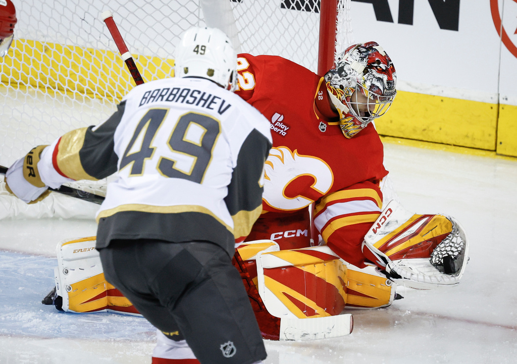Vegas Golden Knights' Ivan Barbashev (49) has his shot grabbed by Calgary Flames goalie Dustin Wolf during the third period of an NHL hockey game in Calgary, Alberta, on Tuesday, Oct. 14, 2025. (Jeff McIntosh/The Canadian Press via AP)