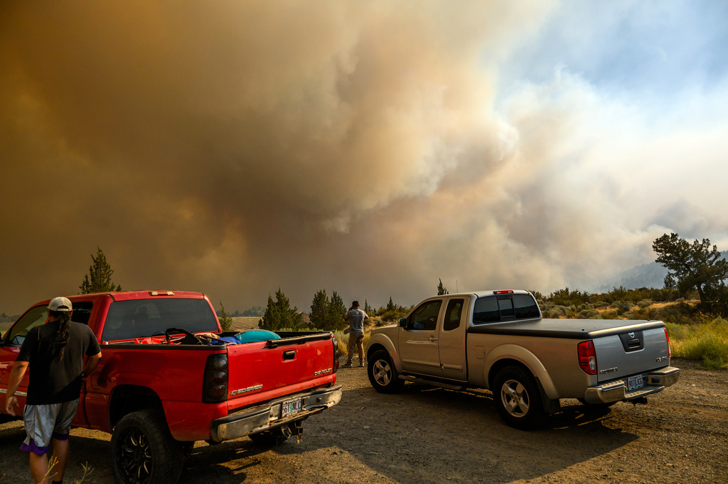 People watch as the Bench fire approaches on Saturday, July 25, 2026, in Warm Springs, Ore. (AP Photo/Noah Berger)