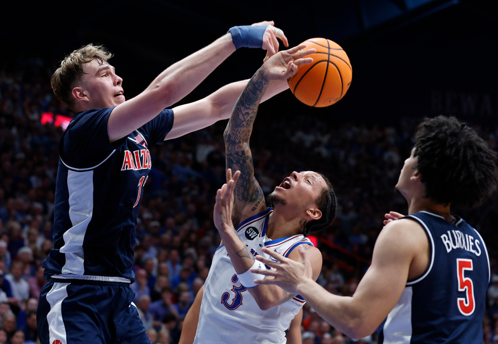 Arizona center Motiejus Krivas, left, blocks a shot by Kansas guard Tre White (3) as Arizona guard Brayden Burries (5) also defends during the first half of an NCAA college basketball game, Monday, Feb. 9, 2026, in Lawrence, Kan. (AP Photo/Colin E. Braley)