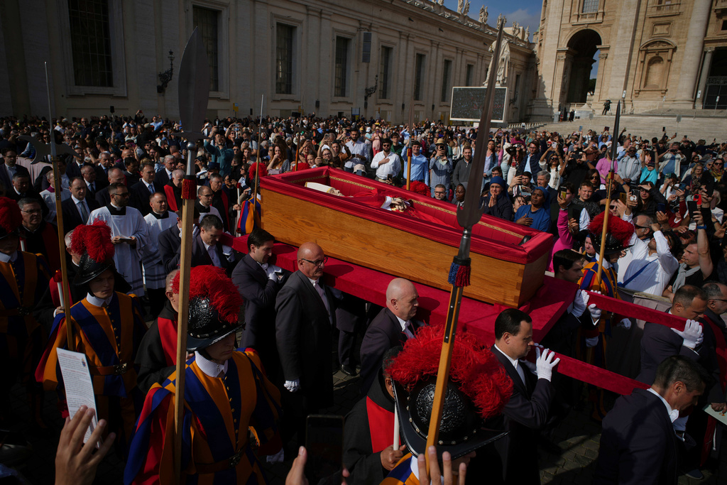 The body of Pope Francis is carried into St. Peter's Basilica to lie in state for three days, at the Vatican, April 23, 2025, (AP Photo/Emilio Morenatti, File)