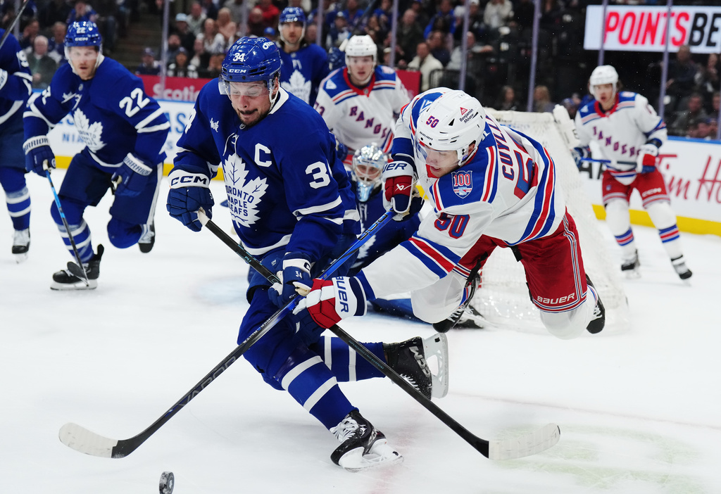 Toronto Maple Leafs' Auston Matthews (34) battles for the puck with New York Rangers' Will Cuylle (50) during first-period NHL hockey game action in Toronto, Thursday, Oct. 16, 2025. (Nathan Denette/The Canadian Press via AP)