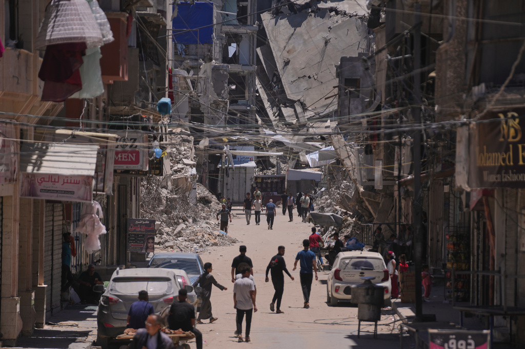 Palestinians walk along a street surrounded by buildings destroyed by Israeli military strikes during the Israel-Hamas war in Khan Younis, southern Gaza Strip, Friday, May 29, 2026. (AP Photo/Abdel Kareem Hana)