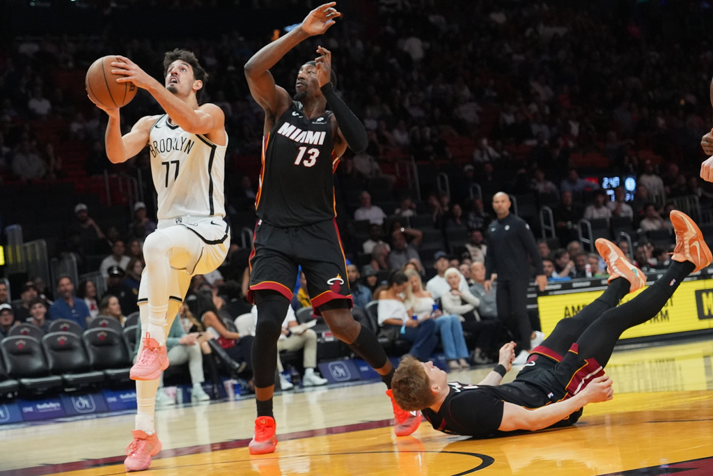 Miami Heat guard Kasparas Jakucionis, right, falls to the court as Brooklyn Nets guard Ben Saraf (77) goes to the basket during the first half of an NBA basketball game, Tuesday, March 3, 2026, in Miami. (AP Photo/Lynne Sladky)