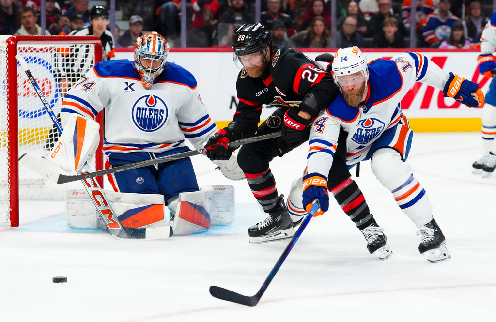 Edmonton Oilers' goaltender Stuart Skinner (74) keeps his eye on the puck as Edmonton Oilers' Mattias Ekholm (14) and Ottawa Senators' Claude Giroux (28) battle it out during second period NHL hockey action in Ottawa on Tuesday, Oct. 21, 2025. (Sean Kilpatrick/The Canadian Press via AP)