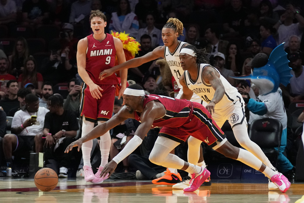 Miami Heat center Bam Adebayo, front, goes for a loose ball against Brooklyn Nets forward Noah Clowney (21) and guard Terance Mann (14) during the first half of an NBA basketball game, Thursday, March 5, 2026, in Miami. (AP Photo/Lynne Sladky)