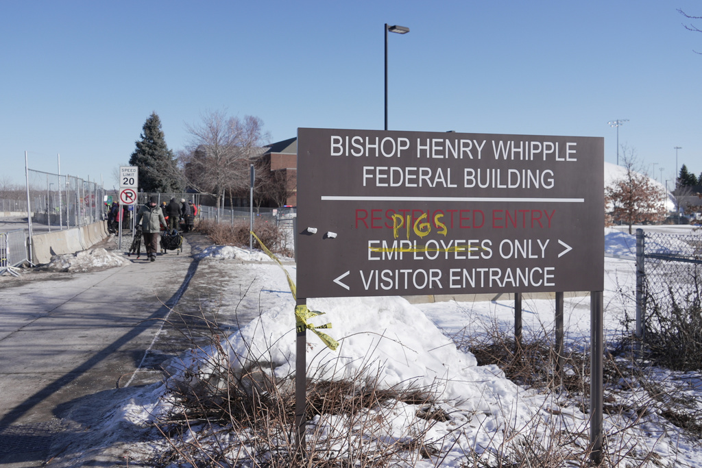FILE - Protesters yell at cars coming and going near a defaced sign for Bishop Whipple Federal building in Minneapolis on Wednesday, Jan. 28, 2026. (AP Photo/Laura Bargfeld, File)