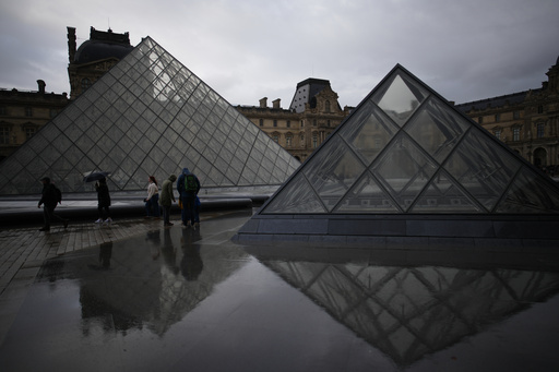 People tour the courtyard of Le Louvre museum in the rain Monday, Oct. 27, 2025 in Paris. (AP Photo/Christophe Ena) People tour the courtyard of Le Louvre museum in the rain Monday, Oct. 27, 2025 in Paris. (AP Photo/Christophe Ena)