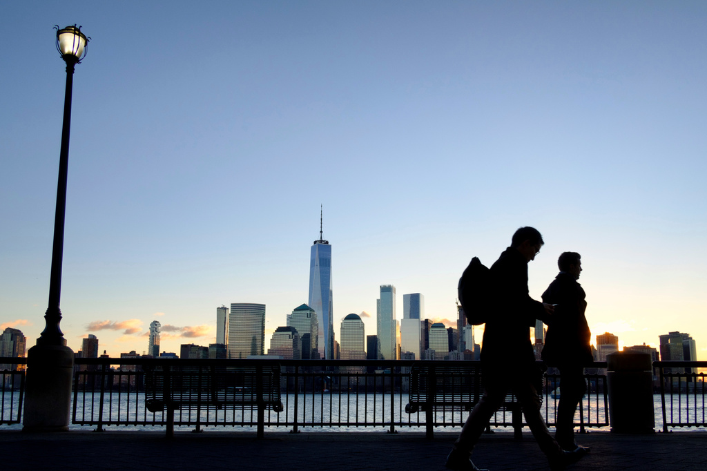 FILE - Early morning commuters on the New Jersey side of the Hudson River walk to work past the New York City skyline, Dec. 18, 2018, in Jersey City, N.J. (AP Photo/J. David Ake, File)