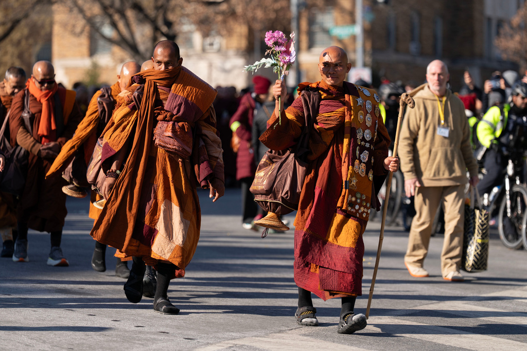 Monk Bhikkhu Pannakara waves as Buddhist monks who are participating in a Walk For Peace walk through a the streets of Washington, Tuesday, Feb. 10, 2026. (AP Photo/Jose Luis Magana)