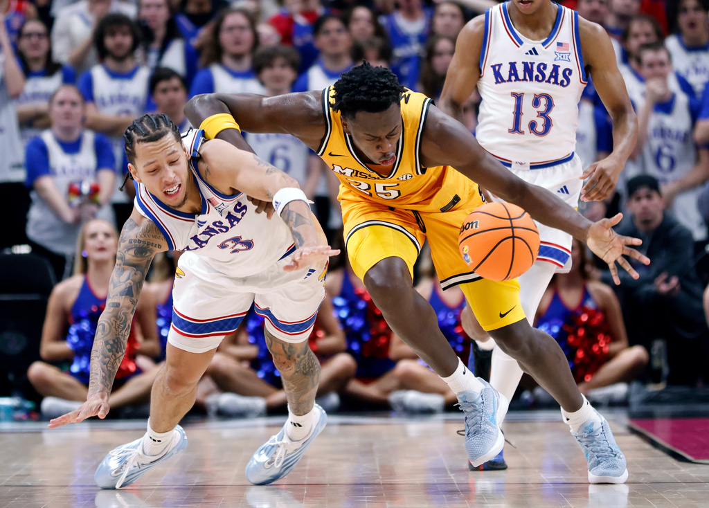 Kansas guard Tre White (3) and Missouri forward Mark Mitchell (25) go after the ball during the first half of an NCAA college basketball game, Sunday, Dec. 7, 2025, in Kansas City, Mo. (AP Photo/Colin E. Braley)