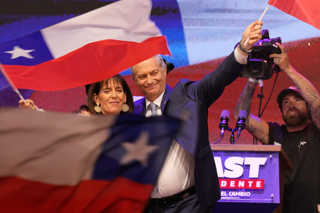 Presidential candidate Jose Antonio Kast, of the opposition Republican Party, and his wife, Maria Pia Adriasola, wave flags after winning the presidential runoff election in Santiago, Chile, Sunday, Dec. 14, 2025. (AP Photo/Matias Delacroix)