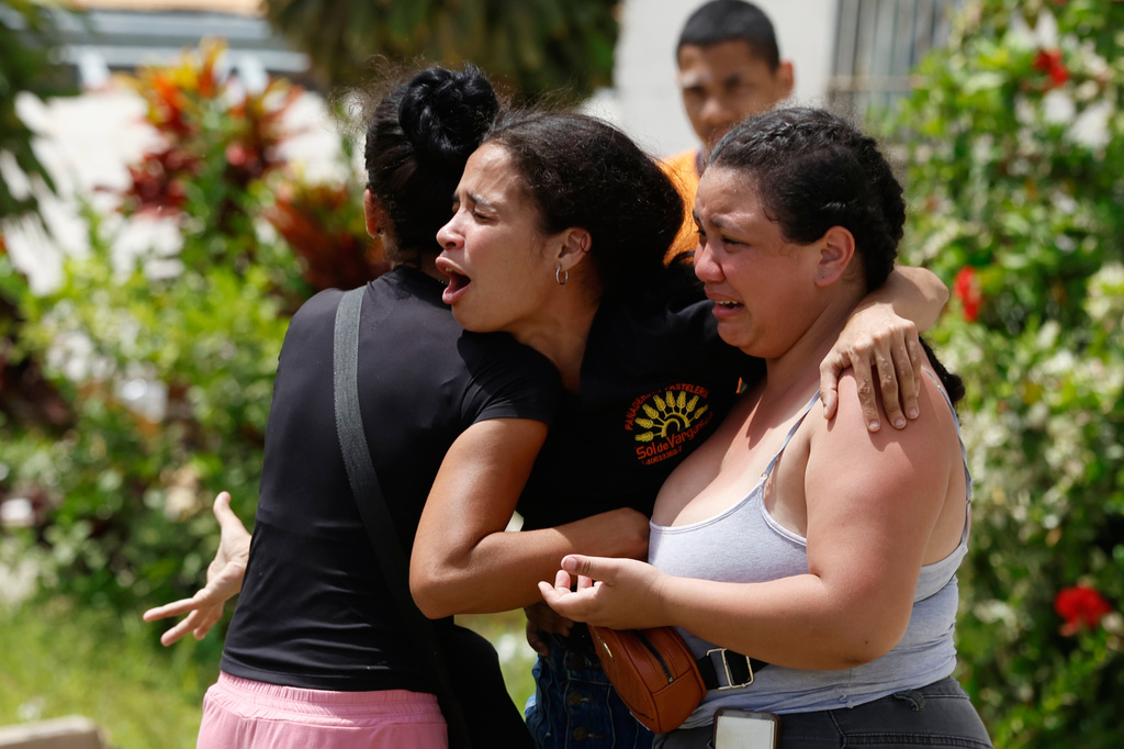 Neighbors comfort Gabriela Rojas, center, as she mourns in front of her damaged home, where two of her children died during earthquakes that struck La Guaira, Venezuela, Thursday, June 25, 2026.. (AP Photo/Pedro Mattey)