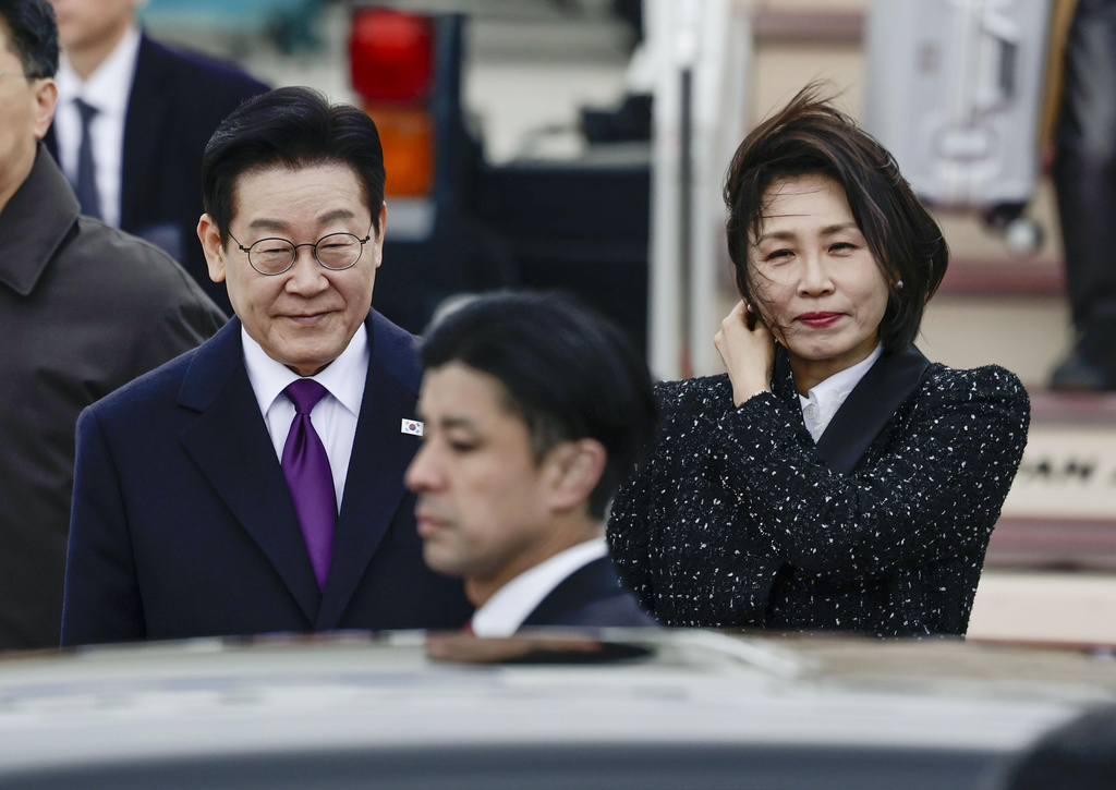 South Korean President Lee Jae Myung, left, and his wife Kim Hea Kyung, right, arrive at Kansai International Airport in Izumisano city, Osaka, western Japan, Tuesday, Jan. 13, 2026. (Kyodo News via AP)