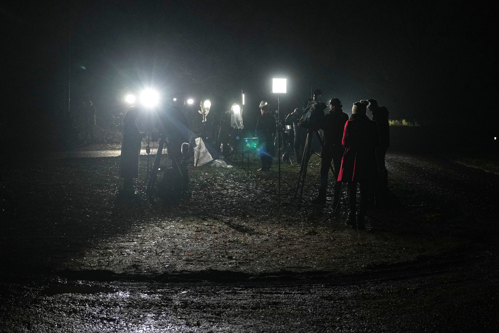 Journalists report at the entrance of the Sandringham Royal Estate in Sandringham, England, Thursday, Feb. 19, 2026 after Andrew Mountbatten-Windsor was arrested by British police on suspicion of misconduct in public office. (AP Photo/Alastair Grant)