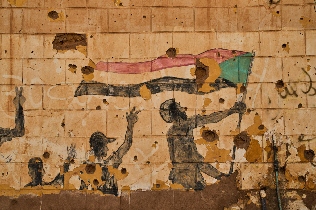 A painting depicting people holding the Sudanese flag is seen on a wall damaged by bullets and shrapnel in Omdurman, on the outskirts of Khartoum, Sudan, Thursday, April 23, 2026. (AP Photo/Bernat Armangue)